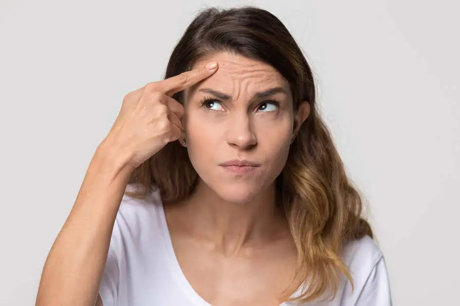 Woman examining forehead wrinkles, considering neurotoxin treatments in McMurray, PA